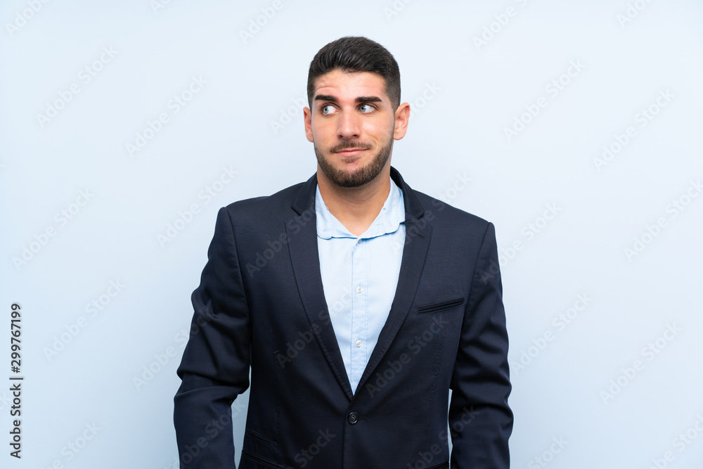 Handsome man over isolated blue background making doubts gesture looking side Handsome man over isolated blue background making doubts gesture looking side