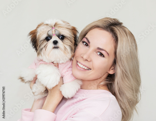 beautiful cute girl holding a well groomed shih tzu puppy in a pink sweater