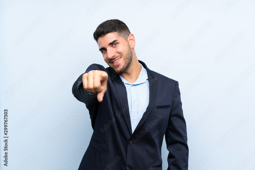 Handsome man over isolated blue background points finger at you with a confident expression Handsome man over isolated blue background points finger at you with a confident expression