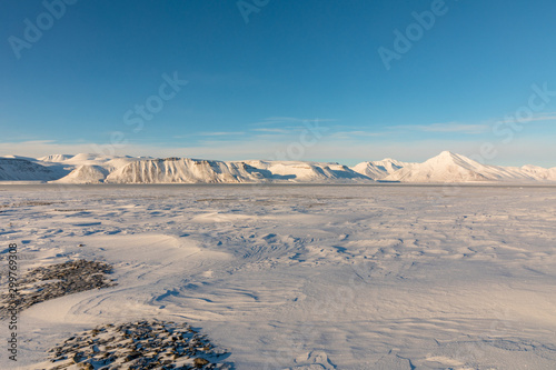 Arctic winter landscape with frozen fjord and snow covered mountains on Svalbard, Norway