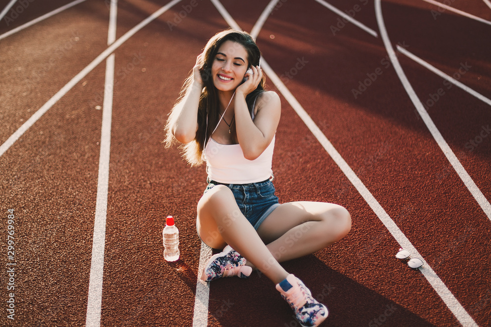 Stylish woman posing for the camera sitting on running track.