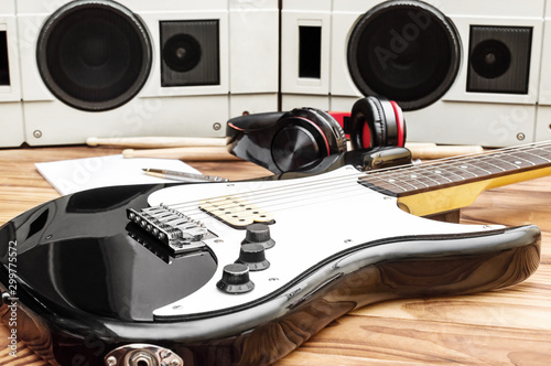 Guitar with drumsticks and audio equipment on wooden desk. photo