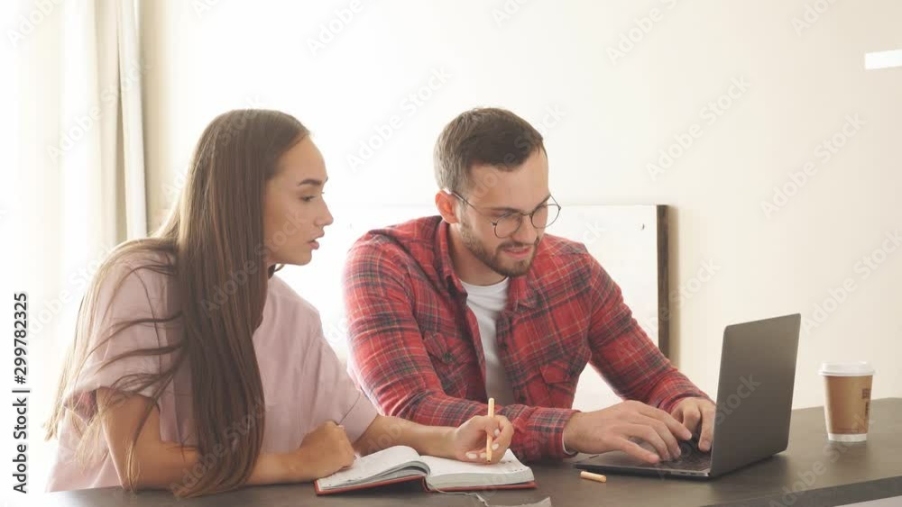 Bright young freelancer discussing with female coworker work related issues, sitting at table, chatting with charming female colleague, expressing positive mood Bright young freelancer discussing with female coworker work related issues, sitting at table, chatting with charming female colleague, expressing positive mood