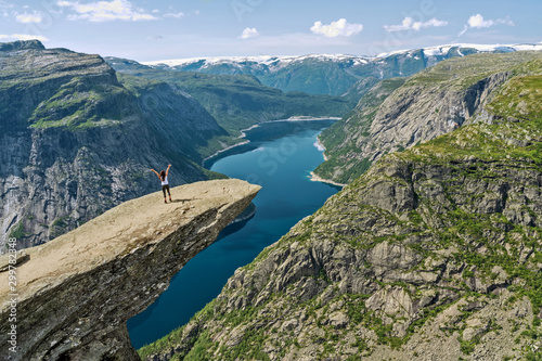 Trolltunga rock above Ringedalsvatnet mountain lake - famous Norwegian hiking tourist landmark with girl standing on the rock.