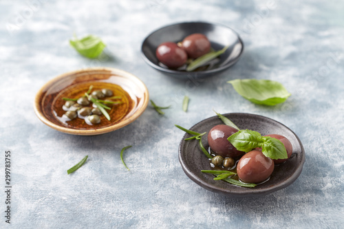 Kalamata olives and capers on bright wooden background. Close up. 