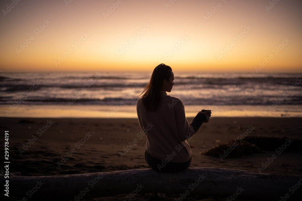 Woman enjoying hot drink on a sunset near ocean Woman enjoying hot drink on a sunset near ocean