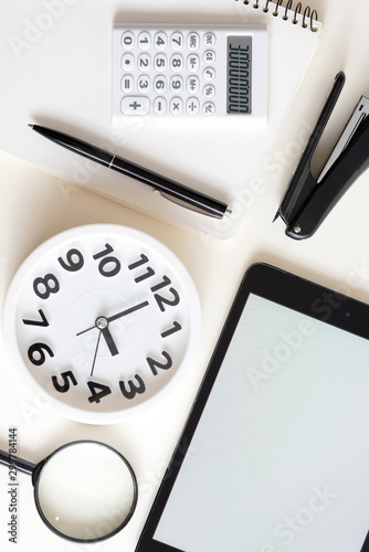 Creative desktop.Modern design, white colors. Office, school ,college . Alarm clock and school, college, business  object. Tablet in the side . Copy space.