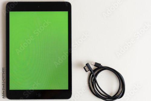 Black touch screen tablet in iPad style with blank green screen area for copy space white background and USB cable