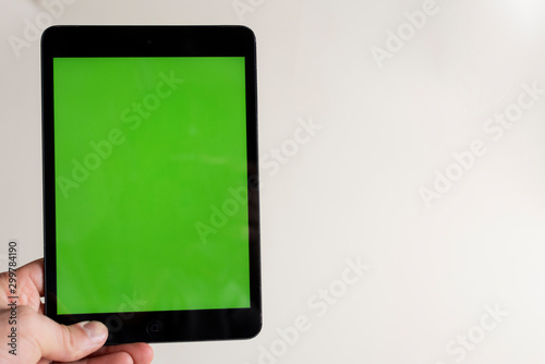 Black touch screen tablet in hand iPad style with blank green screen area for copy space white background