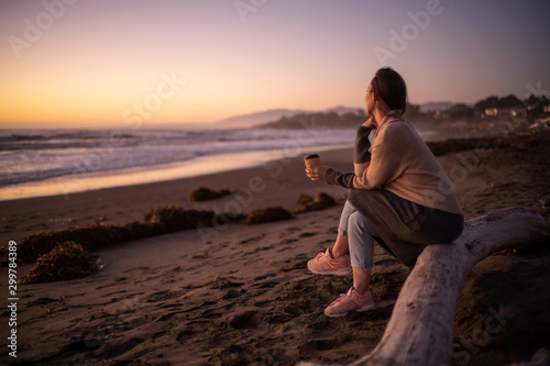 Woman enjoying hot drink on a sunset near ocean © Nejron Photo