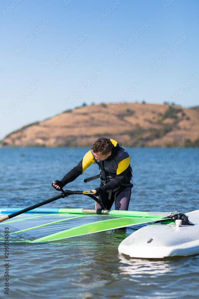 Obraz premium Windsurfer checking his sail and board equipment.