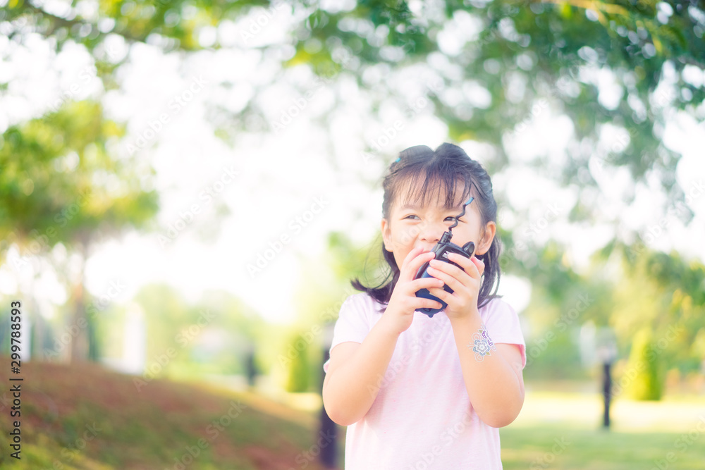 4 years little asian girl playing with walkie-talkie on the park.Happy girl smile and laughing when she plays outside in a playground with a toy walkie talkie radio.
