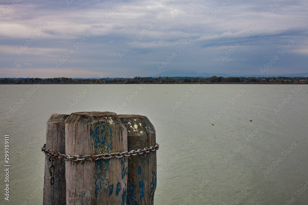 Fototapeta premium Close up of three pillars chained together lake and skyline in the background overcast beautiful skies