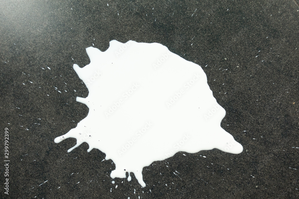 Top view of White milk spilled and splash on the dark floor surface