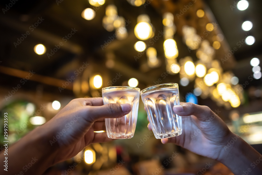Close up shot of group of people clinking glasses with wine or champagne in front of bokeh background
