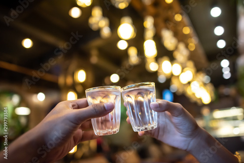 Close up shot of group of people clinking glasses with wine or champagne in front of bokeh background