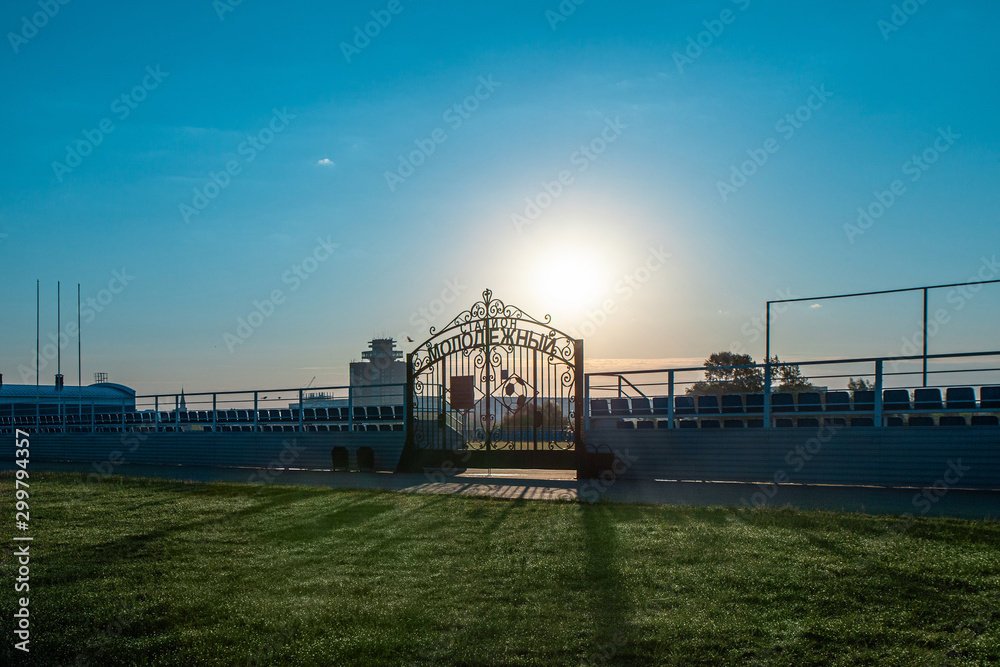 Gate to Youth Stadium early morning with sunlight. Inscription on the gate: Youth Gate to Youth Stadium early morning with sunlight. Inscription on the gate: Youth