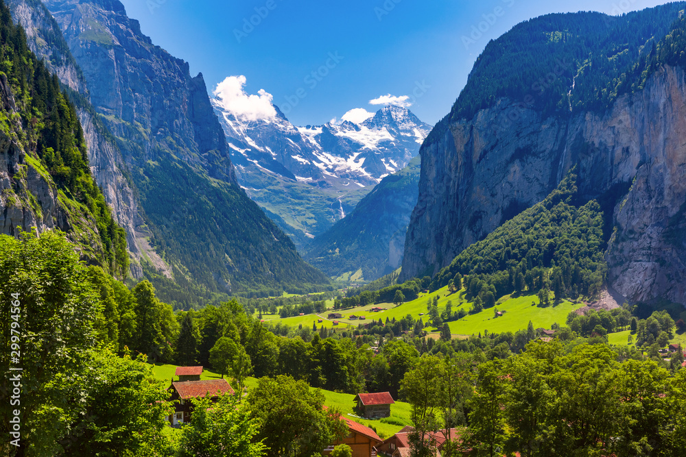 Lauterbrunnen valley, waterfall and the Lauterbrunnen Wall in Swiss Alps, Switzerland. Eiger, Monch and Jungfrau mountains in the background.