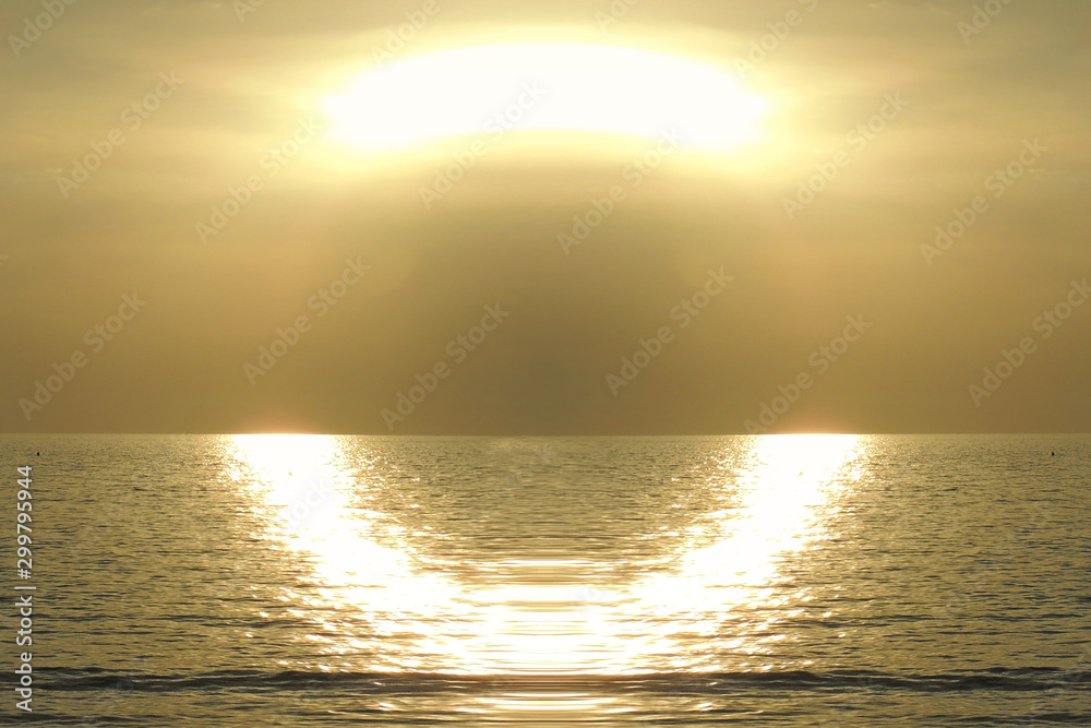 tramonto dorato con riflesso di luce a semicerchio sull'acqua del mare scintillante