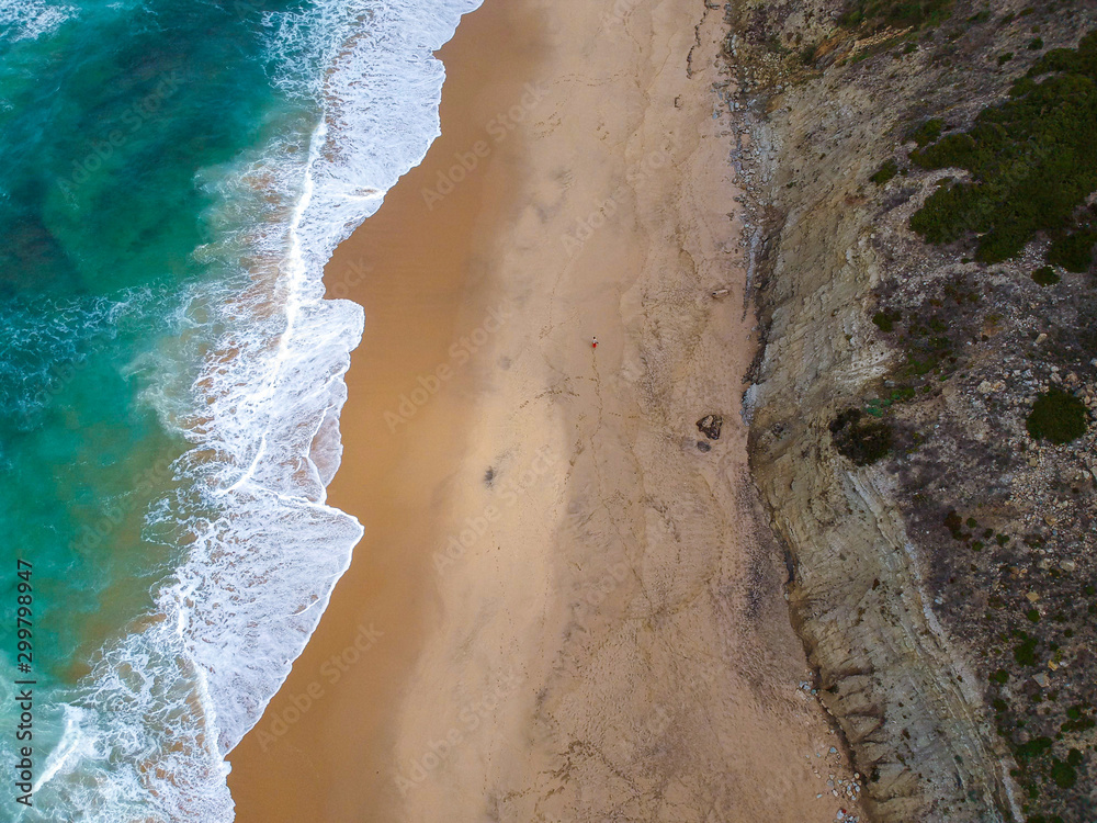 Sand beach aerial, top view of a beautiful sandy beach aerial shot with the blue waves rolling into the shore