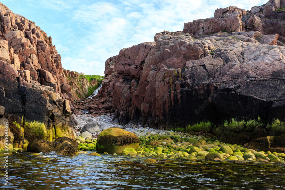 Northern polar summer. Beautiful waterfall on the coastline of Barents sea, Arctic ocean, Kola Peninsula, Russia