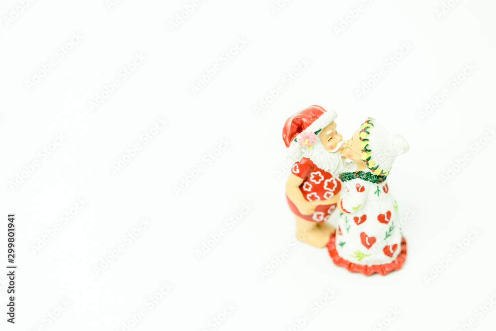Miniature people : Santa Claus and mrs. Claus kissing and hugs in hawaii and ready for work in christmas season on white background.