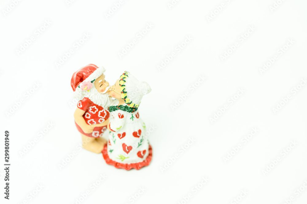 Miniature people : Santa Claus and mrs. Claus kissing and hugs in hawaii and ready for work in christmas season on white background.
