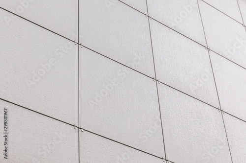 Diagonal close-up of light gray smooth tile on wall surface
