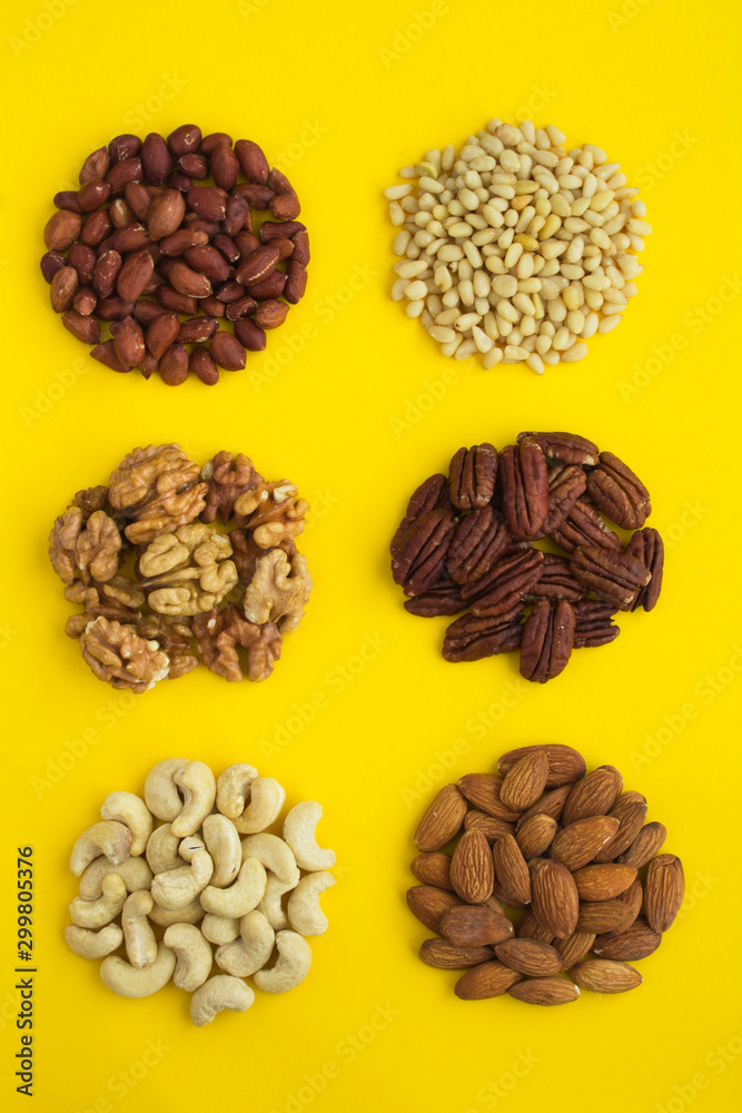 Set of different nuts on the yellow background. Top view. Closeup. Location vertical. Set of different nuts on the yellow background. Top view. Closeup. Location vertical.
