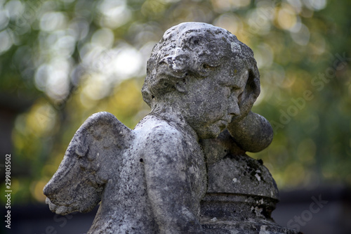 Side view of a sandstone sculpture of an angel in front of a colorful background on an old cemetery in Berlin-Germany.
