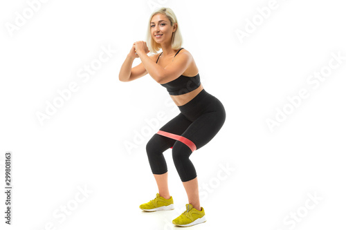 Sport caucasian girl do sports with elastic for fitness and shakes legs muscles isolated on white background