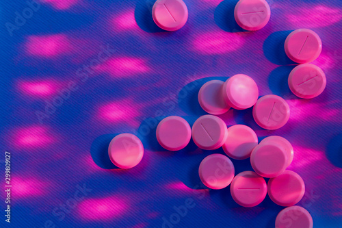 Pink pills over purple background. Pills, drugs, health and medicine concept. Abstract colorful background. Colorful drugs, close up.