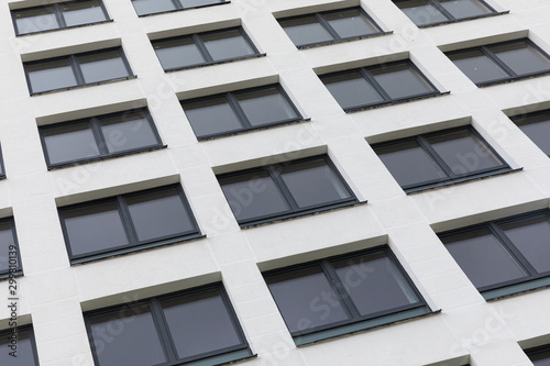 New apartment facade painted white smooth parget and dark black windows, diagonal view, ground view. © Ivan Traimak