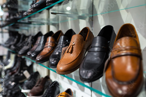 Glass shelves with man's shoes in a shop, focus on shoes