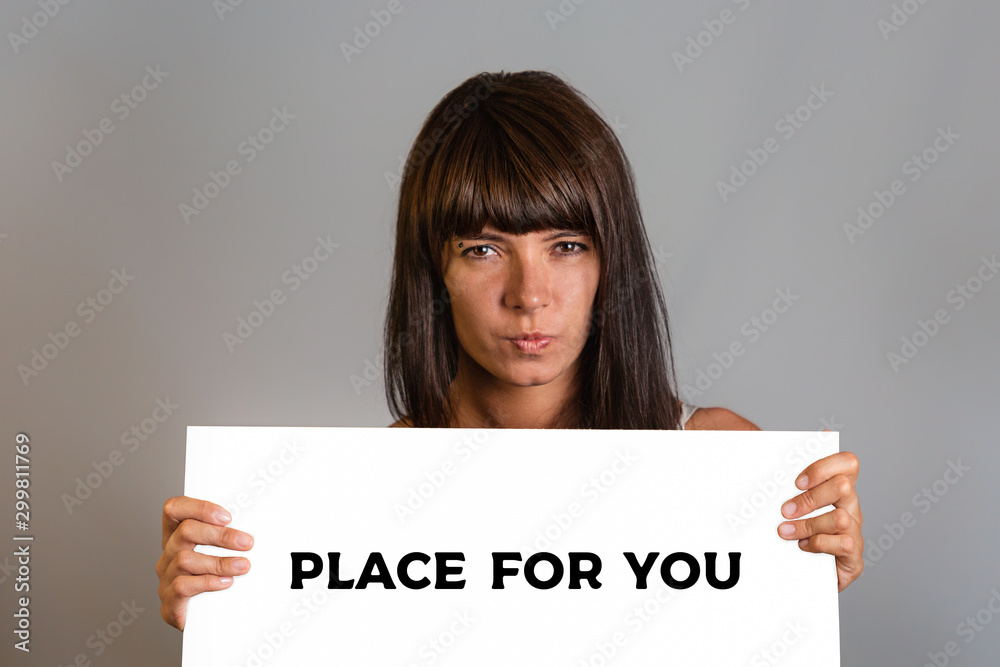 Business and advertising. A young brunette woman with a piercing, holding a cardboard. Gray background. Mock up and copy Business and advertising. A young brunette woman with a piercing, holding a cardboard. Gray background. Mock up and copy