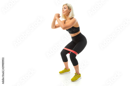 Sport caucasian girl do sports with elastic for fitness and shakes legs muscles isolated on white background