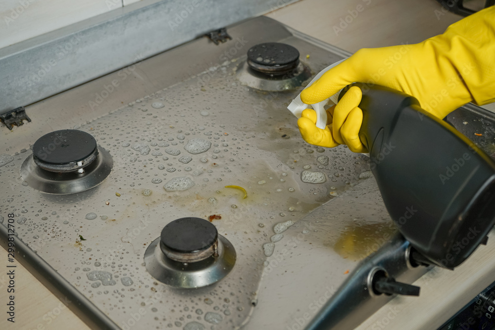 A person cleans and removes complex contaminants on the gas stove using household chemicals.