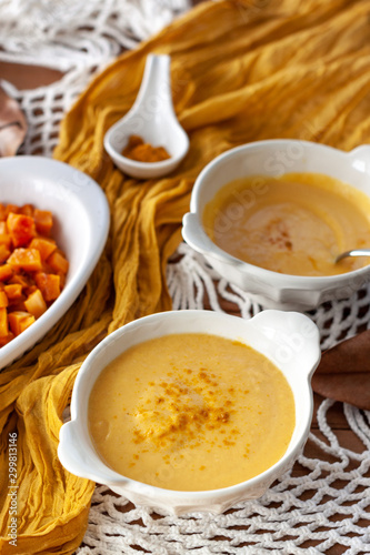 Pumpkin cream spiced with curry in a white bowl with roasted pumpkin and bread. Close Up