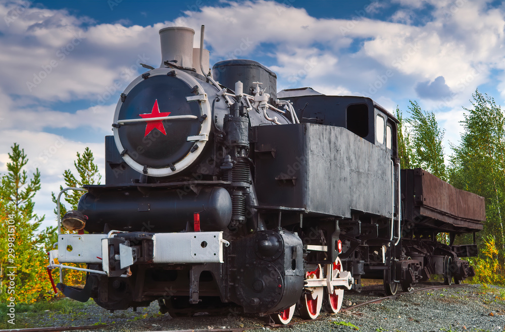 Fototapeta premium Vintage steam train on a background of autumn trees and blue sky.