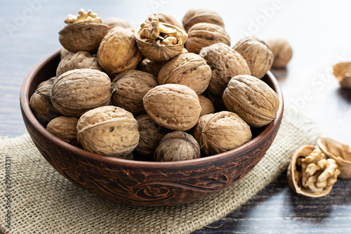 Fresh organic wall\nuts in a clay bowl on rustic wooden background close up.