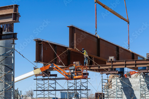 Tableau sur toile Steal workers guiding steal girders into place on temporary scaffolding to support the girders during splicing and bridge deck installation/construction