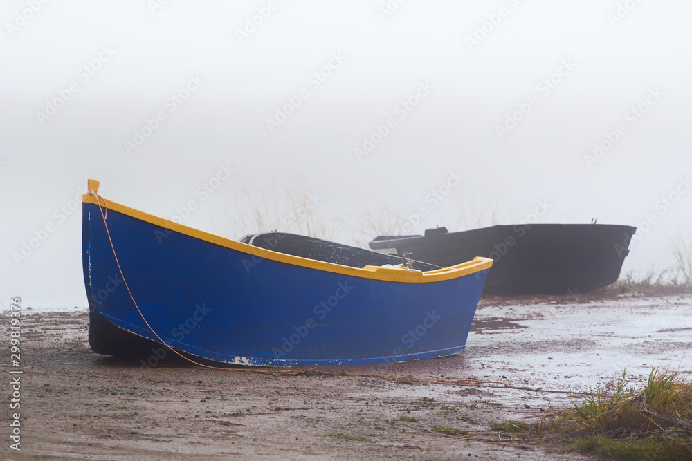 Naklejka premium Small boat on a foggy day during low tide
