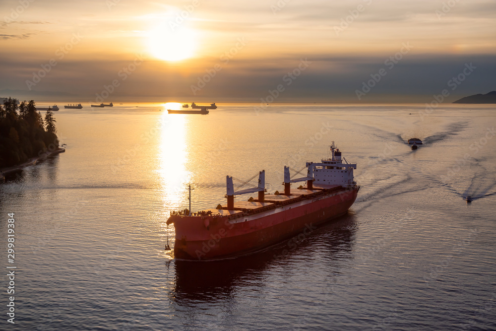 Vancouver, British Columbia, Canada. Aerial View from Above of a Cargo Ship arriving to the Port near Stanley Park during a vibrant sunny sunset.