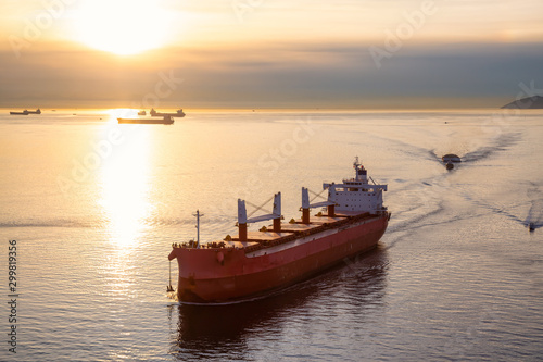 Vancouver, British Columbia, Canada. Aerial View from Above of a Cargo Ship arriving to the Port near Stanley Park during a vibrant sunny sunset.