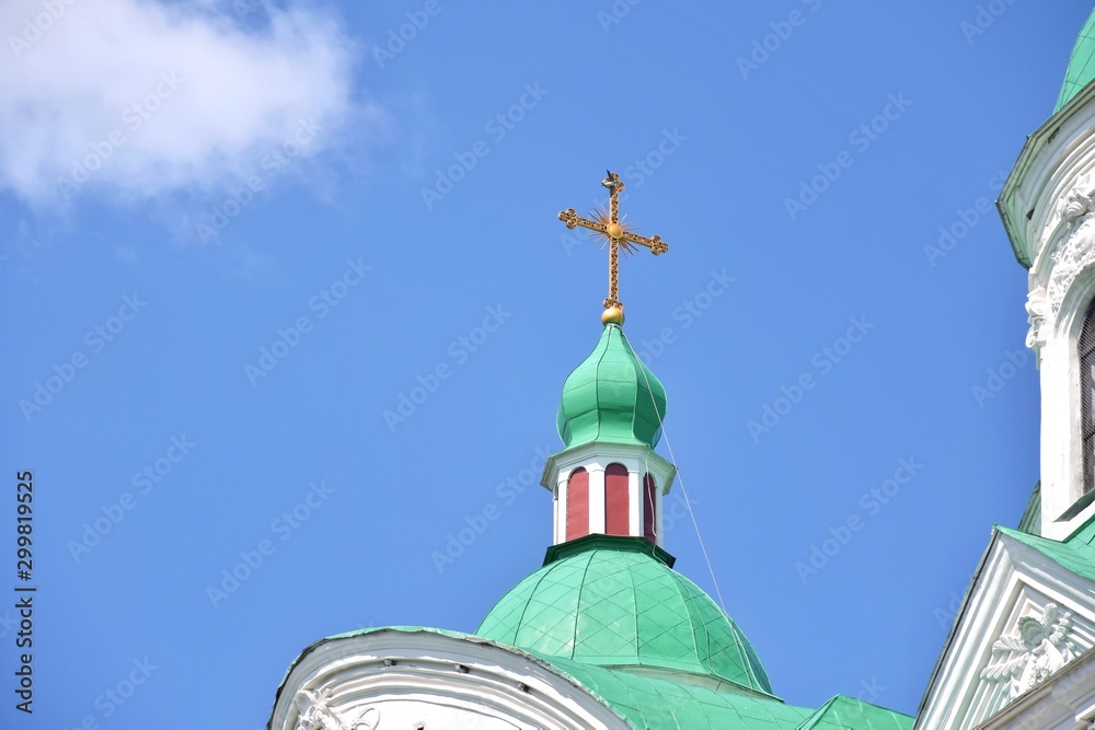 Golden crosses of a christian cathedral on green domes with selective focus on blue sky background. Christian religion.  Easter holidays.  Symbol of faith