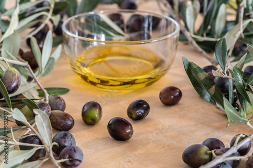 Olive oil in a glass bowl and freshly picked olives