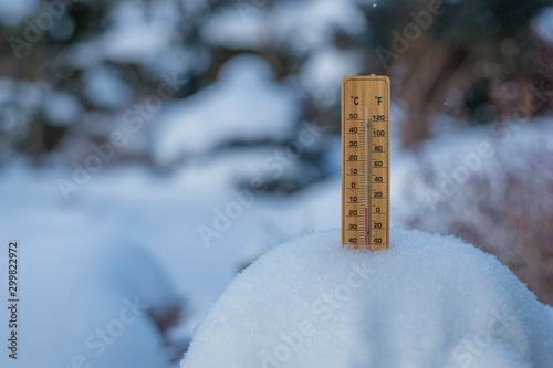 Thermometer on snow shows low temperatures in celsius or farenheit.