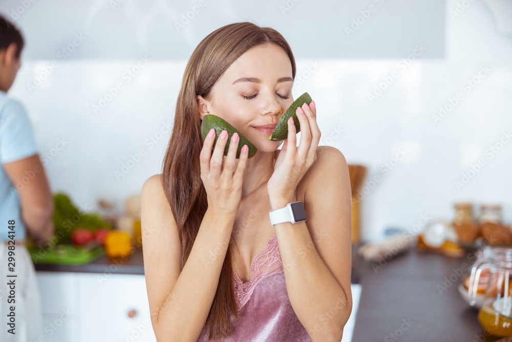 Charming young woman smelling aroma of fresh avocado Charming young woman smelling aroma of fresh avocado