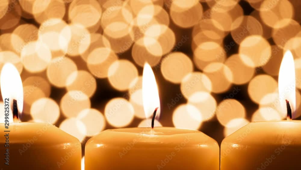 Three Burning Candles in a Row. Three large candles are burning against the backdrop of many burning candles in beautiful bokeh
