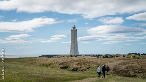 Unidentified people walking towards Malarrif Lighthouse on the Snaefelssnes Peninsula in Iceland.